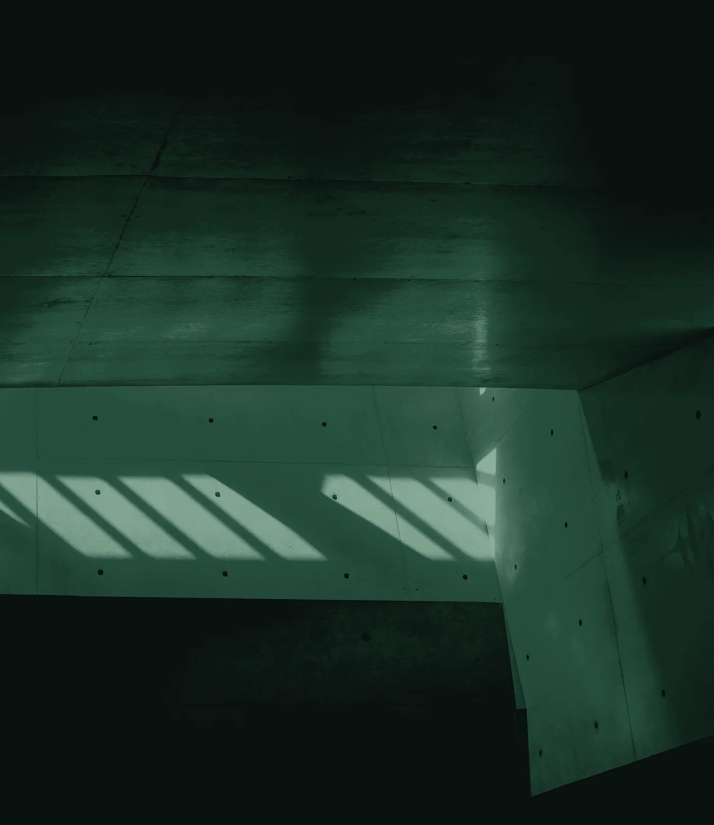 Sunlight falling in bands across a concrete building interior, toned in deep green